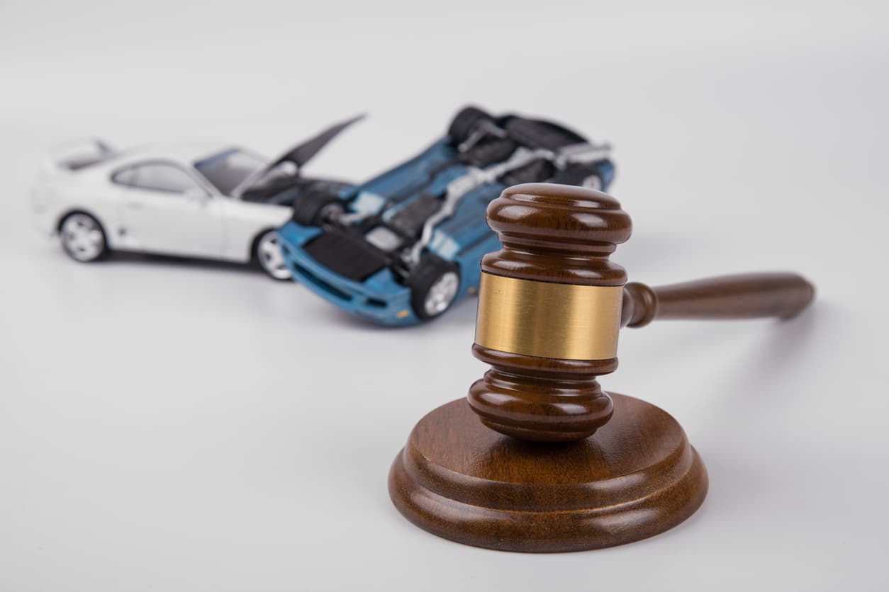 Gavel sits in front of toy cars in a car accident